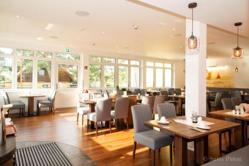 a restaurant with wooden tables and chairs and windows at Ostseehotel Wustrow in Wustrow