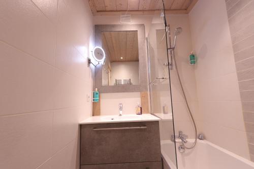 La salle de bains est pourvue d'un lavabo et d'une douche avec un miroir. dans l'établissement Tignes le Lac - Le Santon bel appartement 4 pers, à Tignes