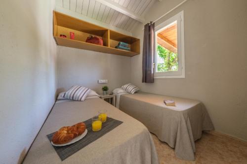 two beds in a room with a plate of croissants at Camping Vendrell Platja in Comarruga