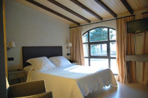 a bedroom with a bed and a large window at Hotel Mas El Cuquello in Els Ibarsos