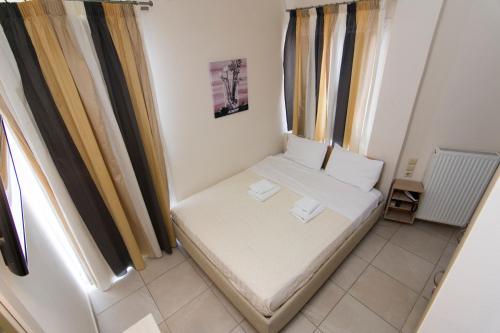 a small white bed in a room with windows at San Nectarios in Parga
