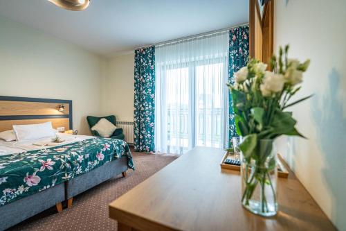 a hotel room with a vase of flowers on a table at Rezydencja Markowy Dworek in Białka Tatrzanska