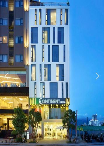 a tall white building with a sign on it at Continent Apartment in Da Nang