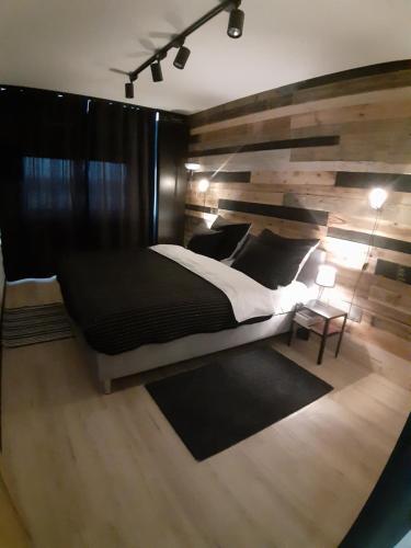a bedroom with a large bed and a wooden wall at Apartament nad Wilgą in Garwolin