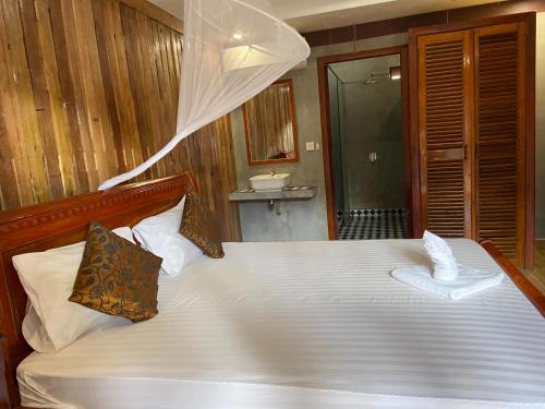 a bedroom with a white bed with a mosquito net at Sothea Angkor Homestay in Phumi Ta Phul