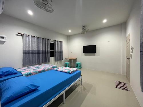 a bedroom with a blue bed and a tv at บ้านคุณย่า in Rayong