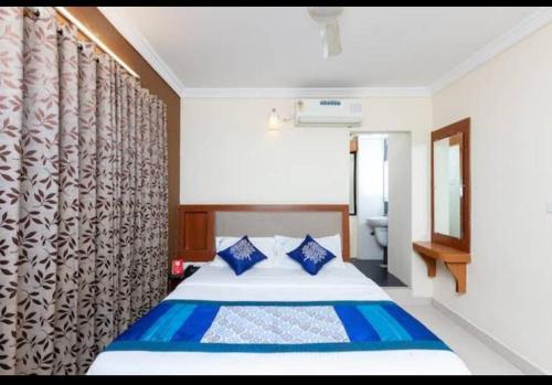a bedroom with a bed with blue pillows at HOTEL MALABAR PLAZA in Chennai