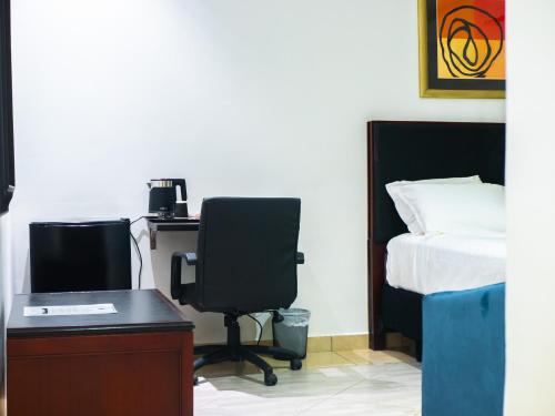 a bedroom with a bed and a desk and a chair at KoKo Palm Inn LTD in Accra