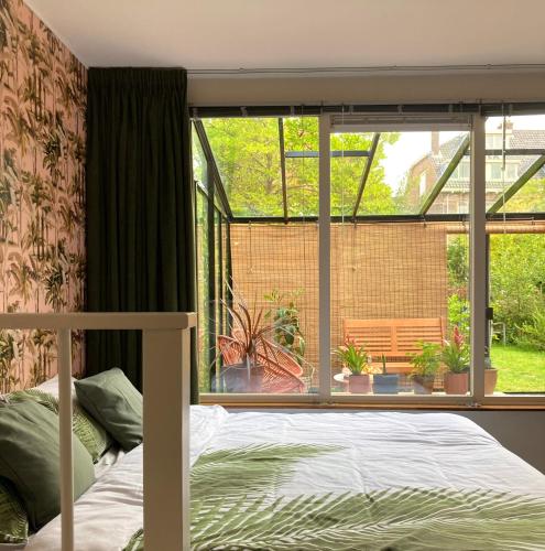a bedroom with a bed in front of a window at B&B Berglust Rotterdam met serre en gratis parkeren in Rotterdam
