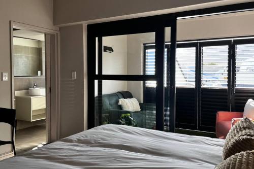 a bedroom with a bed and a view of a bathroom at Hermanus Waterfront Apartment No.19 in Hermanus