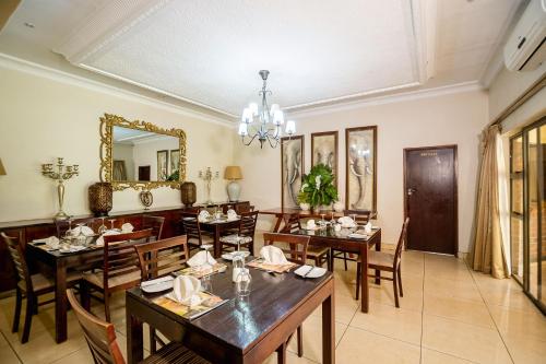 a dining room with tables and chairs and a mirror at The Victoria Falls Deluxe Suites in Victoria Falls