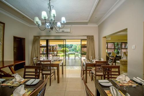a dining room with tables and chairs and a chandelier at The Victoria Falls Deluxe Suites in Victoria Falls