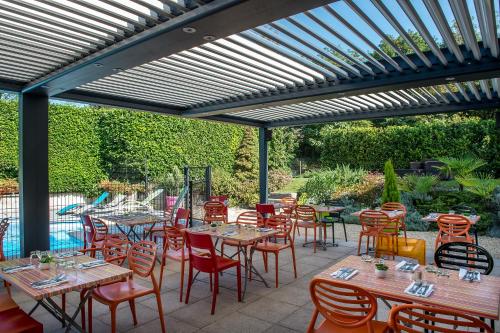 a patio with tables and chairs under a pergola at Logis Le Relais de Sassenage in Sassenage