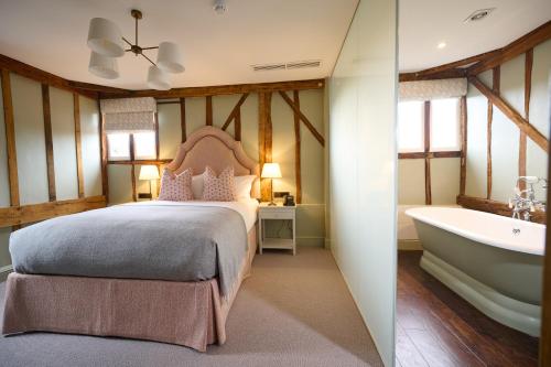 1 dormitorio con cama y bañera en The Angel Inn, Stoke-by-Nayland, en Stoke-by-Nayland