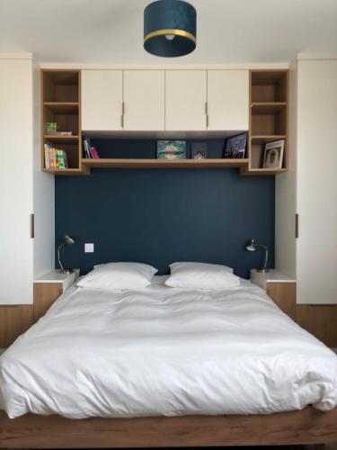 1 dormitorio con 1 cama blanca grande y pared azul en Vue mer exceptionnelle, en Dinard