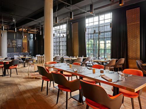 a restaurant with wooden tables and chairs and windows at Mövenpick Zagreb in Zagreb