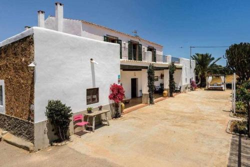 a white building with a bench in front of it at Cas Catalá Sant Jordi in Sant Jordi