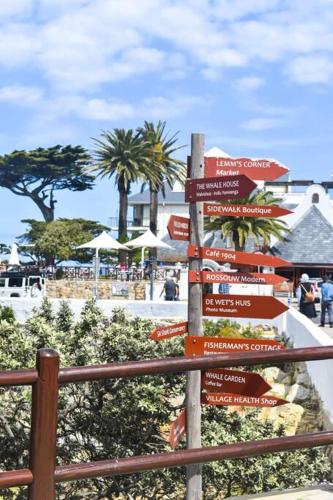 a street sign with many signs on a fence at Hermanus Waterfront Apartment No.20 in Hermanus