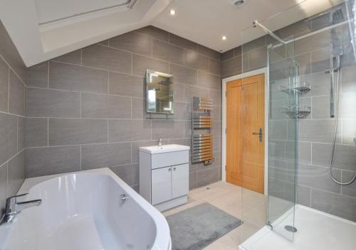 a bathroom with a tub and a glass shower at Bwthyn Nant Bach in Dolbenmaen