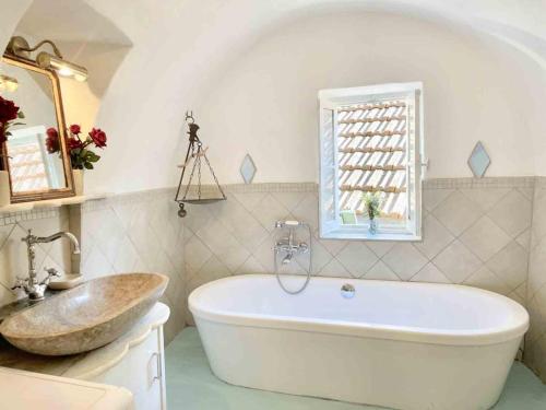 een badkamer met een bad, een wastafel en een raam bij Casa Via Orsini Isolabona Liguria Italy Sleeps 5 in Isolabona