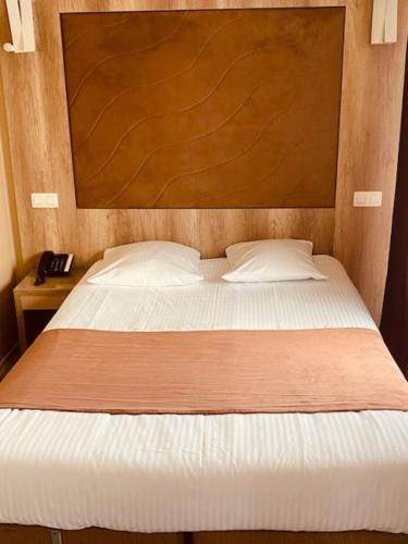 a bedroom with a large bed with a wooden headboard at Hotel Phenix in Brussels