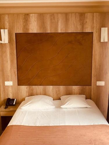 a bed with a wooden headboard and a telephone at Hotel Phenix in Brussels