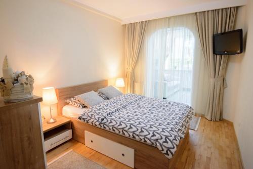 um quarto com uma cama, uma televisão e uma janela em Apartament Eliza em Poiana Brasov