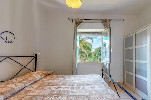 ein Schlafzimmer mit einem Bett und einem großen Fenster in der Unterkunft Villa Eden in Avola