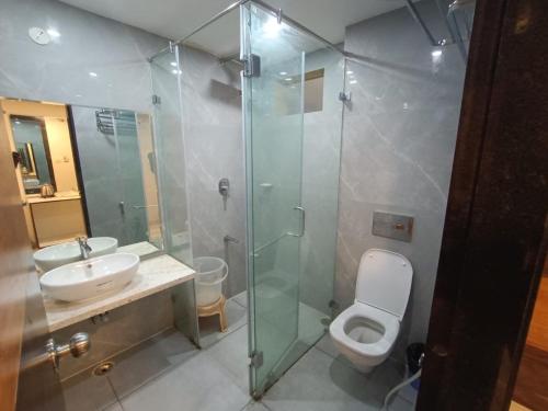 a bathroom with a shower and a toilet and a sink at Hotel Woodside Prestige in Tirupati