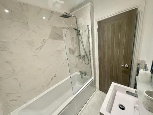 a bathroom with a shower and a tub and a sink at Exquisite apartment, stone throw from the beach in Bournemouth