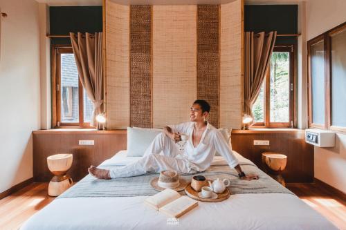 a woman sitting on a bed in a room at The Spa Koh Chang Resort in Ko Chang