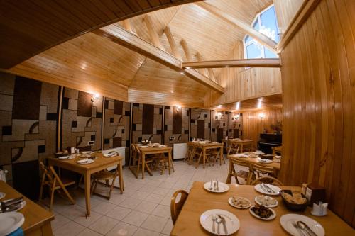 a restaurant with wooden tables and chairs and a large window at Ozon Gudauri in Gudauri