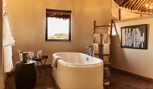 a bathroom with a large tub and a window at Tawi Lodge in Amboseli