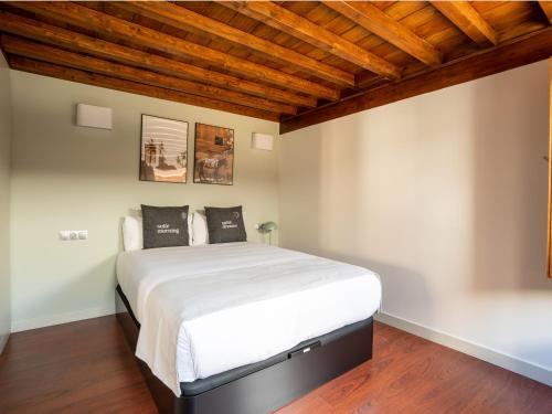 a bedroom with a large bed with wooden ceilings at Limehome Granada Calle Mirasol in Granada
