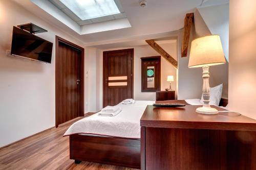a bedroom with a bed and a desk with a lamp at Hotel Charlotta in Jedlina-Zdrój