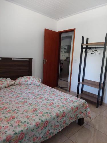 1 dormitorio con cama con colcha de flores y escalera en Apartamento 1 - Palmares - Paty do Alferes, en Paty do Alferes