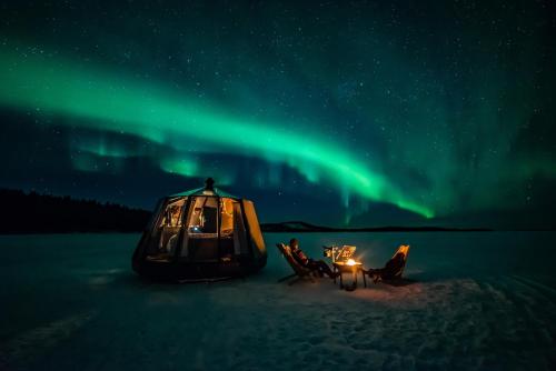 a tent in the snow under the northern lights at Aurora hut igloo in Rovaniemi