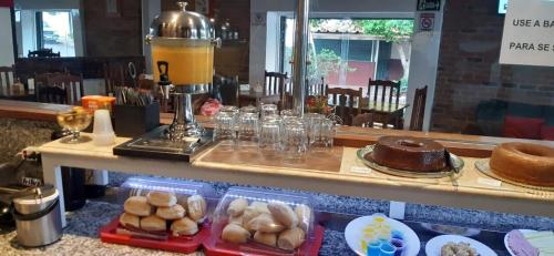 a counter with a table with some bread and cakes at Bento palace hotel in Assis