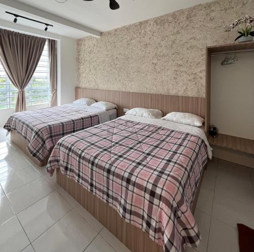 two beds in a bedroom with a plaid blanket at Cameron Emerald Avenue @ Brinchang in Cameron Highlands