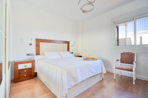 a bedroom with a white bed and a chair at PENTHOUSE NEAR BEACH AND MALAGA TOWN also monthly hire and long term RENTAL CAR AVAILABLE in Málaga
