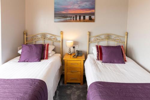two beds in a room with purple and white at Furzedown Hotel in Great Yarmouth