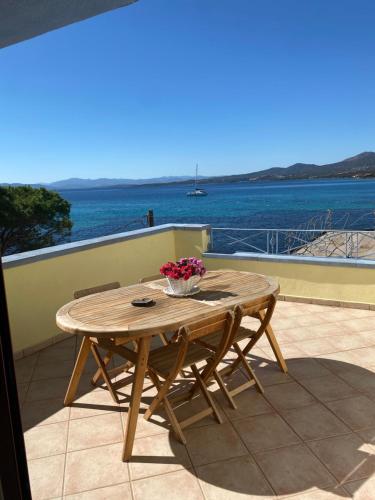 a wooden table on a patio with a view of the water at Hotel Tabby in Golfo Aranci