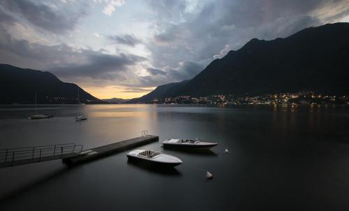 two boats are docked at a dock on a lake at Villa Làrio Lake Como in Pognana Lario