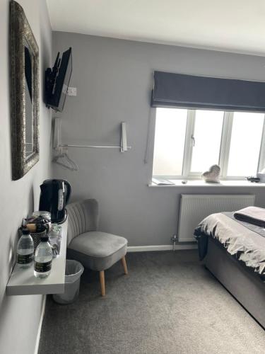 een slaapkamer met een bed, een stoel en een raam bij No1 Guest House in Stamford