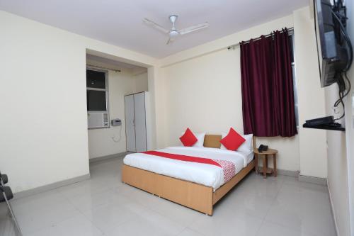 a bedroom with a bed with red pillows and a television at Mannat Residency in Ghaziabad