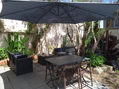 a table and chairs under an umbrella on a patio at Les Oliviers de Camargue in Salin-de-Giraud