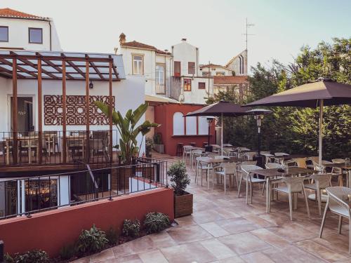 un patio al aire libre con mesas, sillas y sombrillas en PATE'O Hostel & Suites, en Ovar