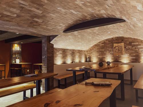 ein Restaurant mit Holztischen und Ziegelwand in der Unterkunft PATE'O Hostel & Suites in Ovar