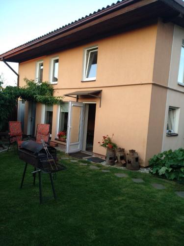a house with two chairs and a grill in the yard at Namelis uždarame kieme in Šiauliai