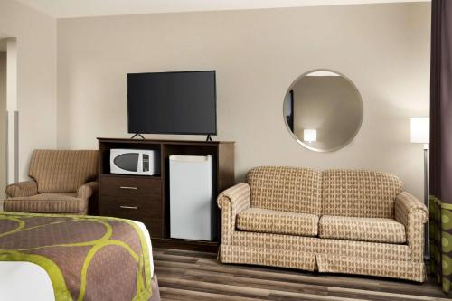 a hotel room with a couch and a tv and a mirror at Super 8 by Wyndham Sarnia ON in Sarnia